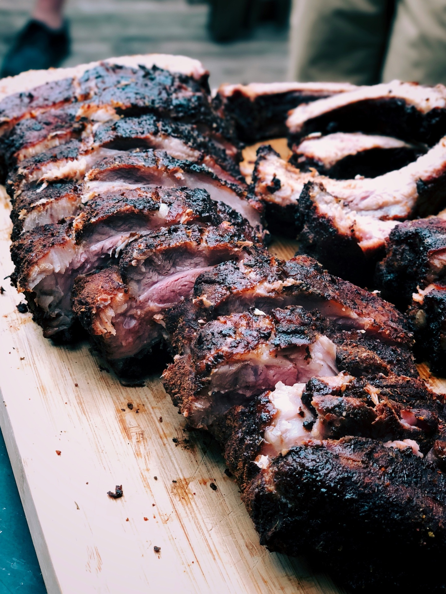 Pepper-crusted smoked ribs sliced on a cedar board